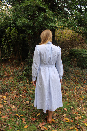 Back of the Calico Day Dress in blue on a woman standing in a lawn