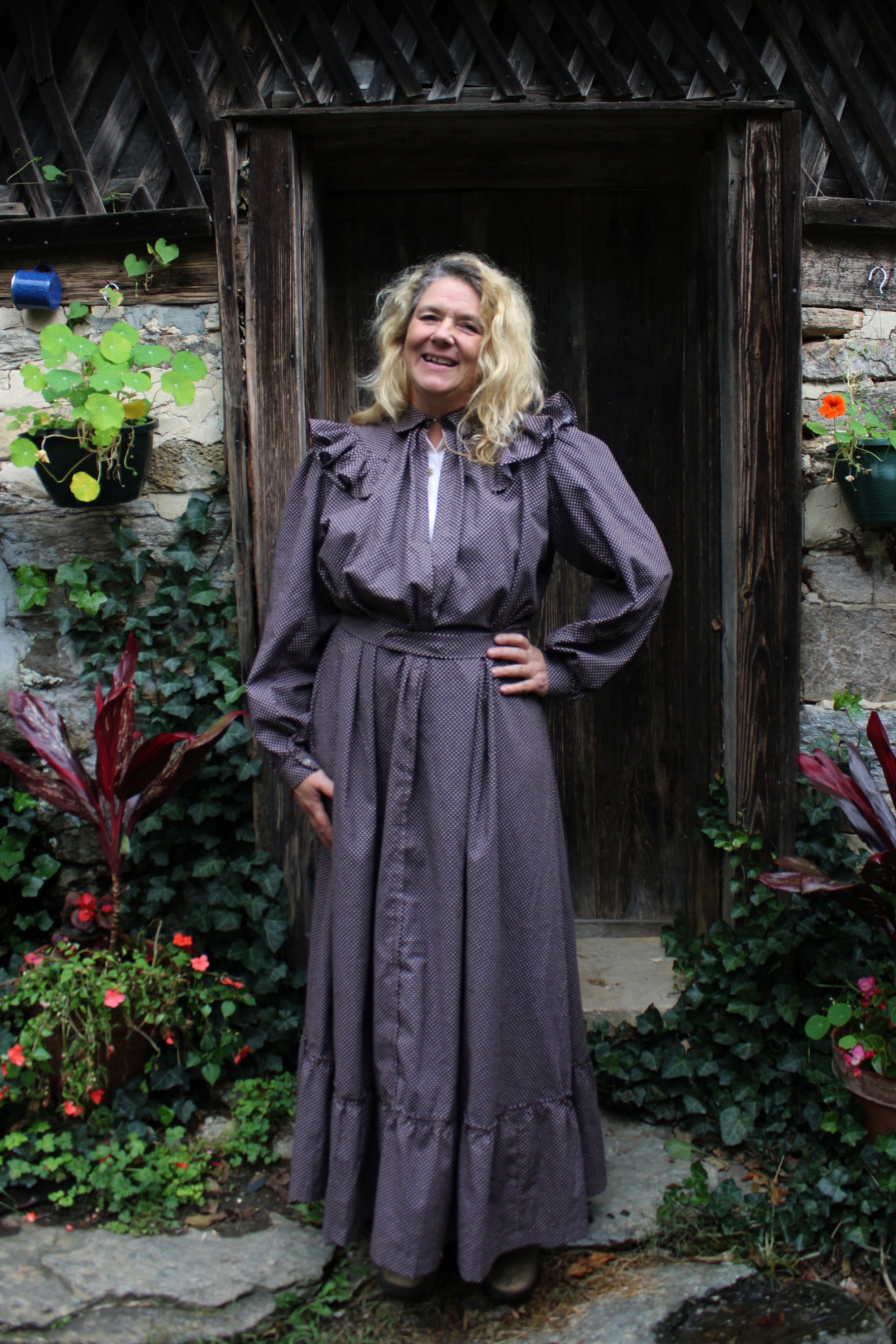 Brown calico day dress on a woman standing by a doorframe with flowers