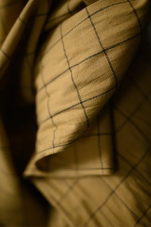 close up A greeny tan and black windowpane check fabric on a dark grey background