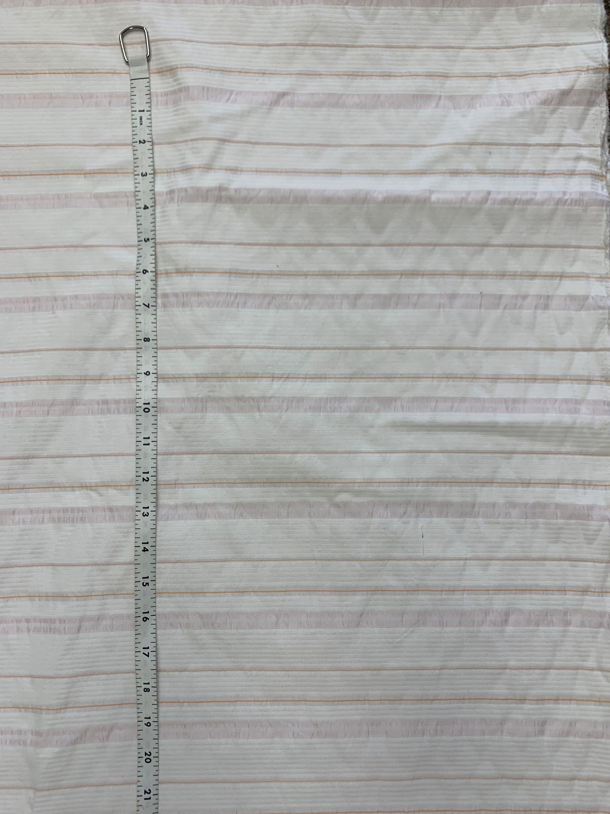 fabric is cotton poly blend with horizonal stripes of white, light pink and orange with measuring tape of the left side