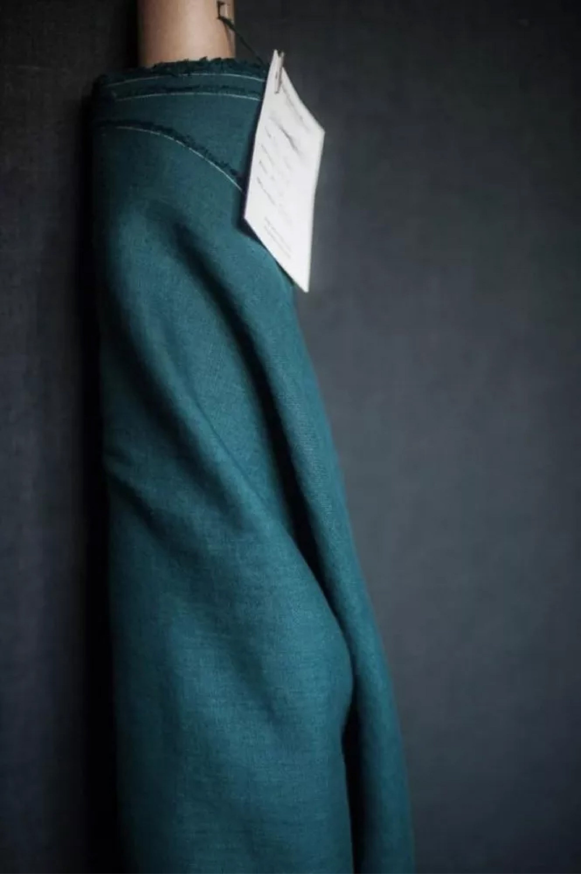 roll of deep blue green linen on a dark grey background.